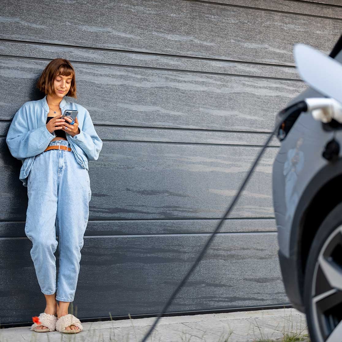 Frau überprüft Ladestand des Autos am Handy